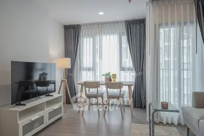 Modern living room with large windows, stylish furniture, and natural light.