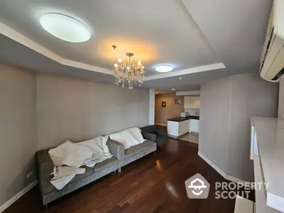 Spacious living room with elegant chandelier and cozy seating area in modern apartment.