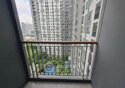 Modern high-rise apartment balcony with cityscape view and lush greenery below.