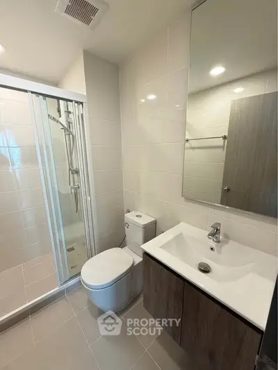 Modern bathroom with sleek shower and stylish vanity in contemporary apartment.