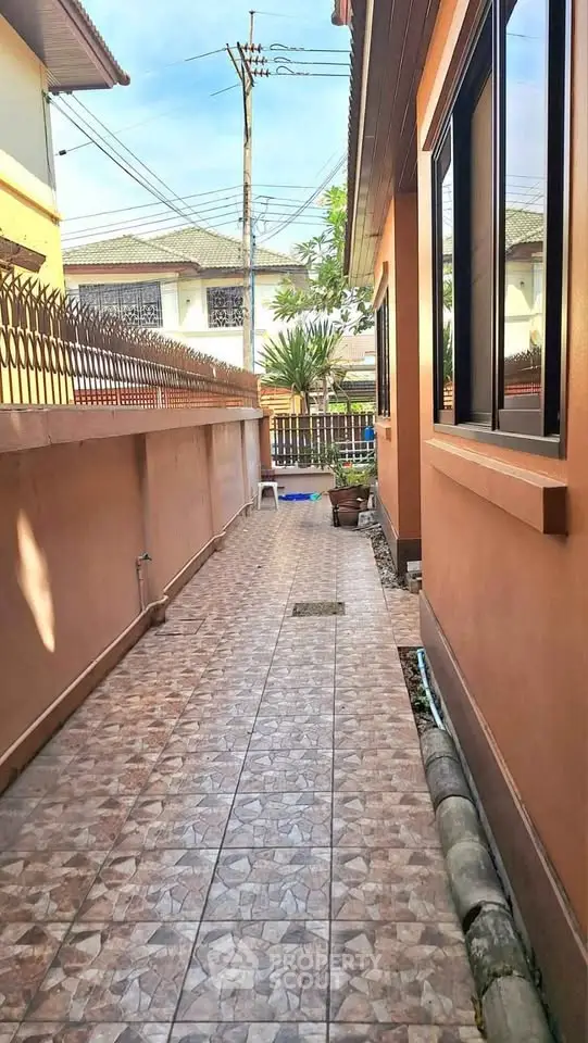 Charming side pathway of a suburban home with tiled flooring and fenced boundary, perfect for privacy.