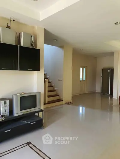 Spacious living area with modern appliances and sleek staircase in a contemporary home.