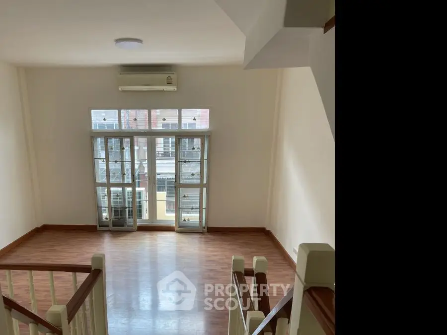 Spacious living room with large windows and wooden flooring in a modern apartment.