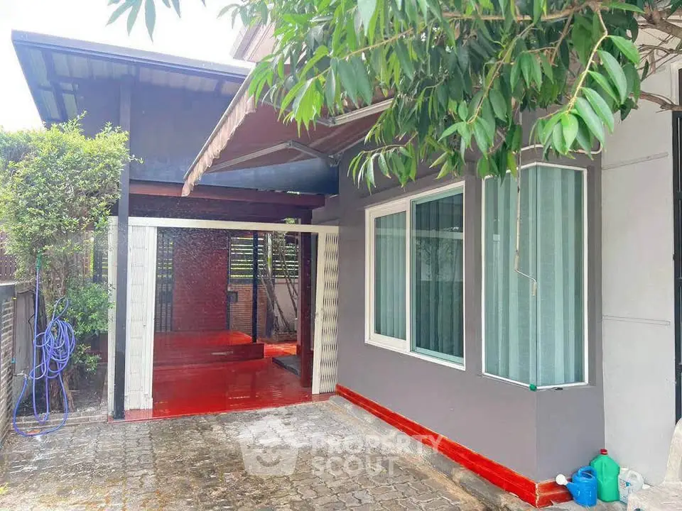 Charming house exterior with covered carport and lush greenery, perfect for family living.