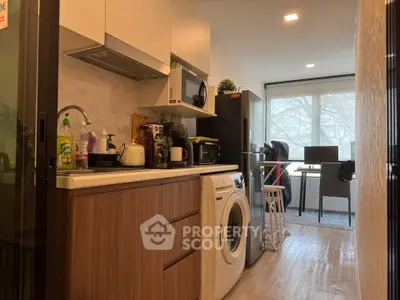 Modern kitchen with washing machine and open layout leading to a bright dining area.