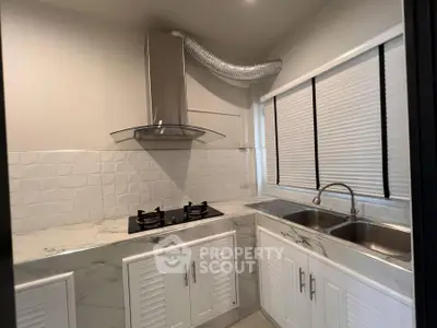 Modern kitchen with marble countertops and gas stove, featuring sleek cabinetry and dual sinks.