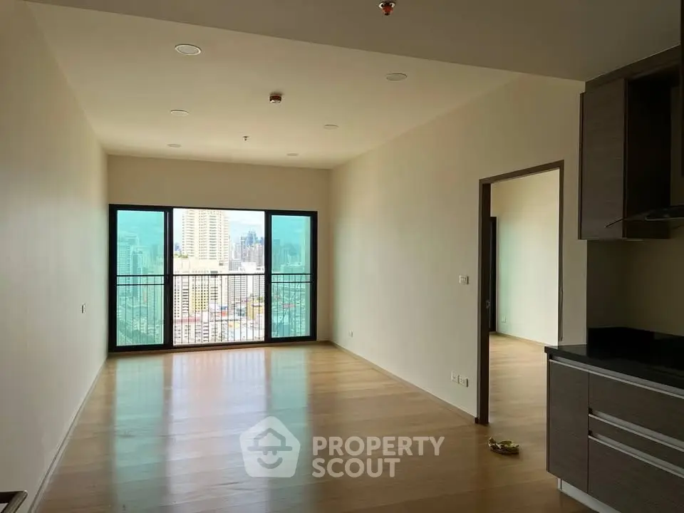 Spacious modern living room with large windows offering stunning city views in a high-rise apartment.