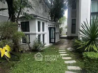 Charming garden pathway leading to a modern building entrance with lush greenery