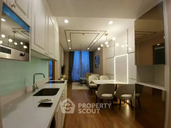 Modern open-layout kitchen and dining area with sleek design and elegant lighting.