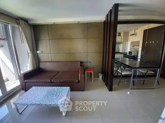 Spacious living area seamlessly connects to a modern kitchen, boasting ample natural light, sleek furnishings, and a welcoming ambiance for entertaining.