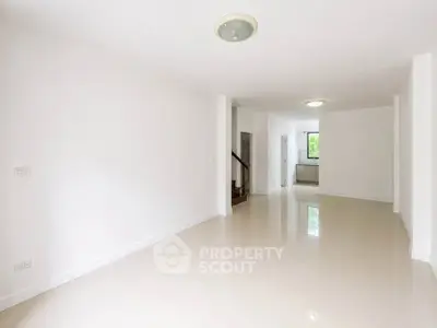 Spacious and bright living room with modern white tiles and ample natural light.