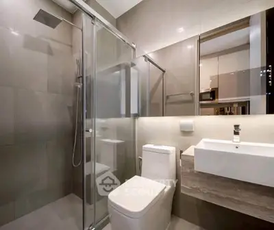 Modern bathroom with glass shower, sleek sink, and neutral tiles