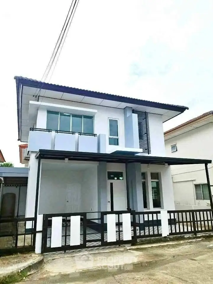 Modern two-story house with sleek design and balcony in a suburban neighborhood.