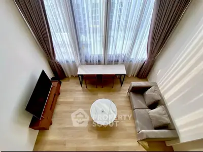 Modern living room with high ceiling and large windows, featuring a cozy sofa and sleek TV setup.