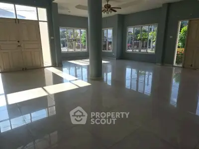 Spacious sunlit living room with large windows and elegant tile flooring.