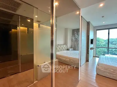 Luxurious bedroom with mirrored closets and large windows offering a serene view of greenery.