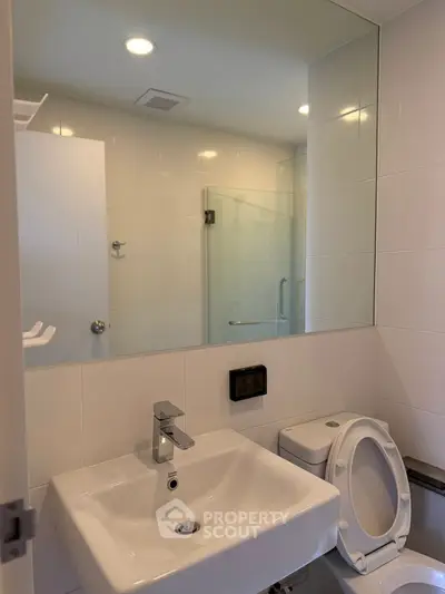 Modern bathroom with sleek fixtures and large mirror in a contemporary home.