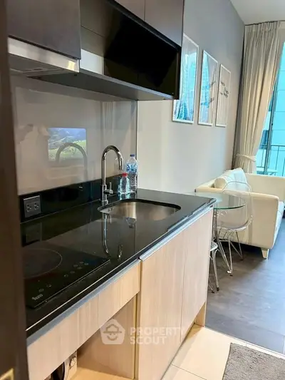 Modern kitchen with sleek design and cozy living area in a stylish apartment.