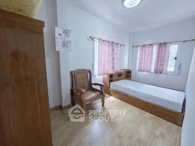 Cozy bedroom with wooden furniture and natural light, perfect for relaxation.