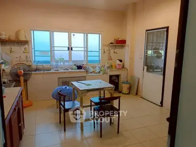 Cozy kitchen with dining area and natural light, featuring a closed layout and tiled flooring.
