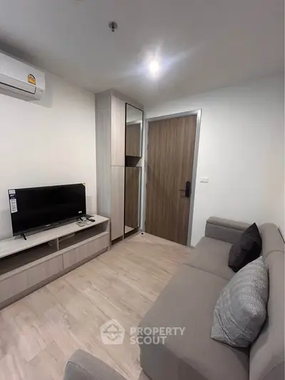 Modern living room with sleek furniture and neutral tones, featuring a cozy sofa and flat-screen TV.