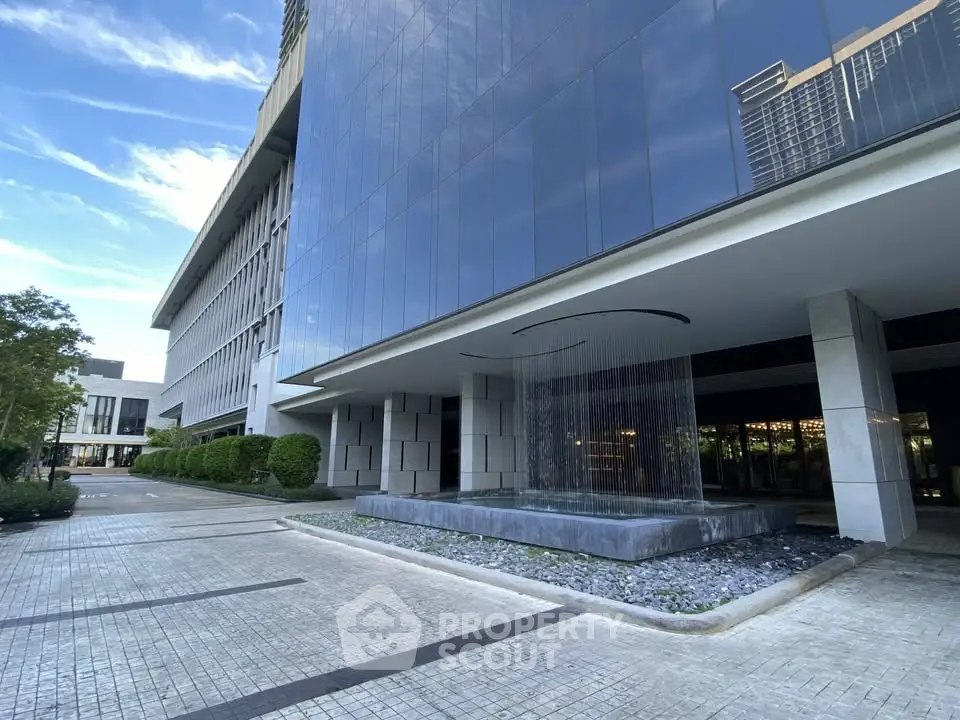 Modern building exterior with sleek design and water feature, showcasing luxury real estate appeal.