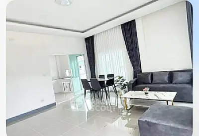 Modern living room with elegant decor and dining area, featuring sleek furniture and large windows.