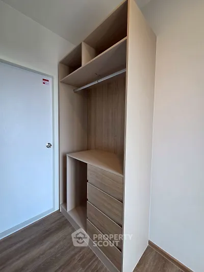 Modern built-in wooden wardrobe with drawers and hanging space in a stylish interior.
