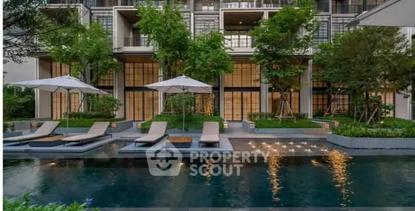 Luxurious modern apartment building with poolside relaxation area and lush greenery.