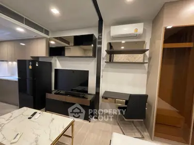 Modern living room with sleek furniture and integrated kitchen area, featuring a stylish black TV unit.