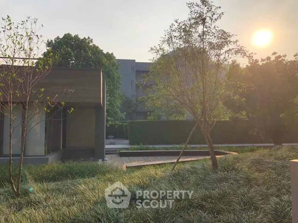 Modern residential building with lush garden and serene sunset view.