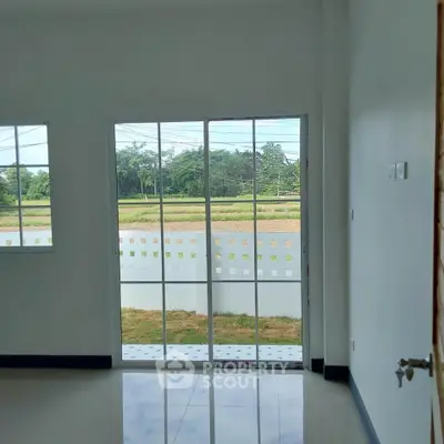 Bright room with large glass sliding doors opening to a scenic view of greenery.