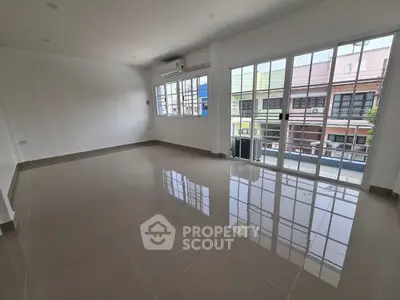 Spacious empty living room with large windows and balcony access in modern apartment.