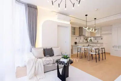 Modern open-layout living room with stylish decor and dining area, featuring elegant lighting and cozy ambiance.