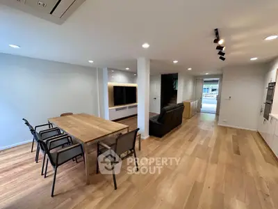 Spacious open-plan living and dining area with modern furnishings and wooden flooring.