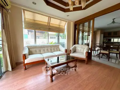 Charming living room with elegant wooden furniture and large windows for natural light.