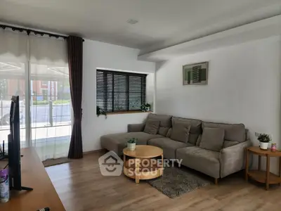 Modern living room with cozy sofa, wooden flooring, and large window for natural light.