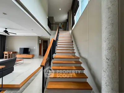 Modern open-plan living room with stylish staircase and sleek interior design.