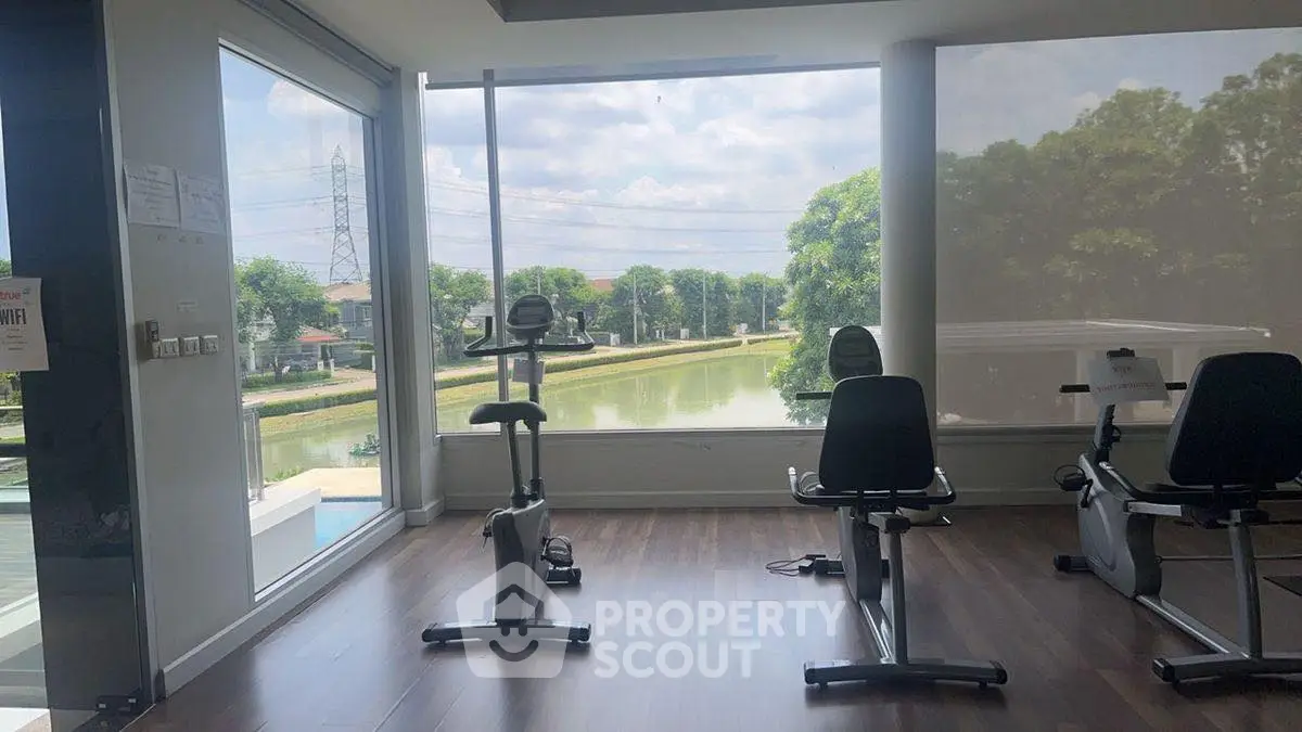 Modern gym with exercise bikes and scenic river view through large windows.