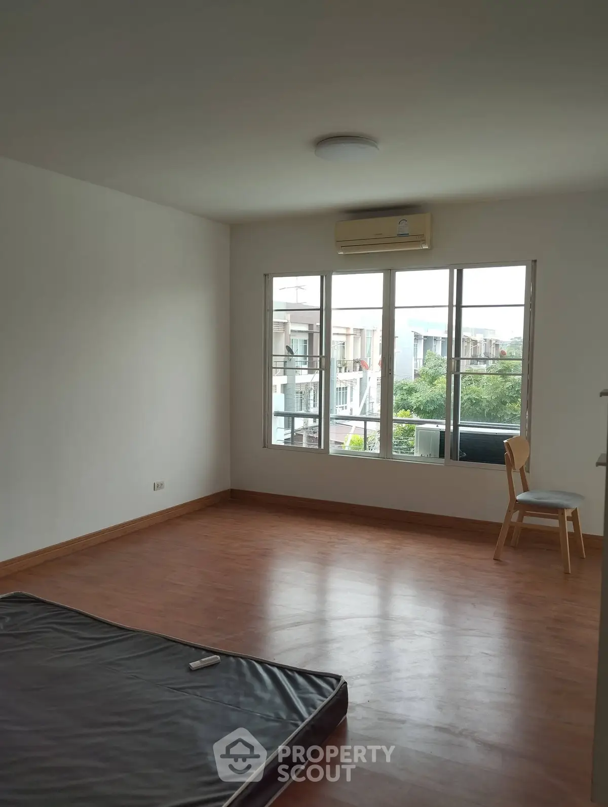 Spacious unfurnished room with large window and air conditioning, perfect for customization.