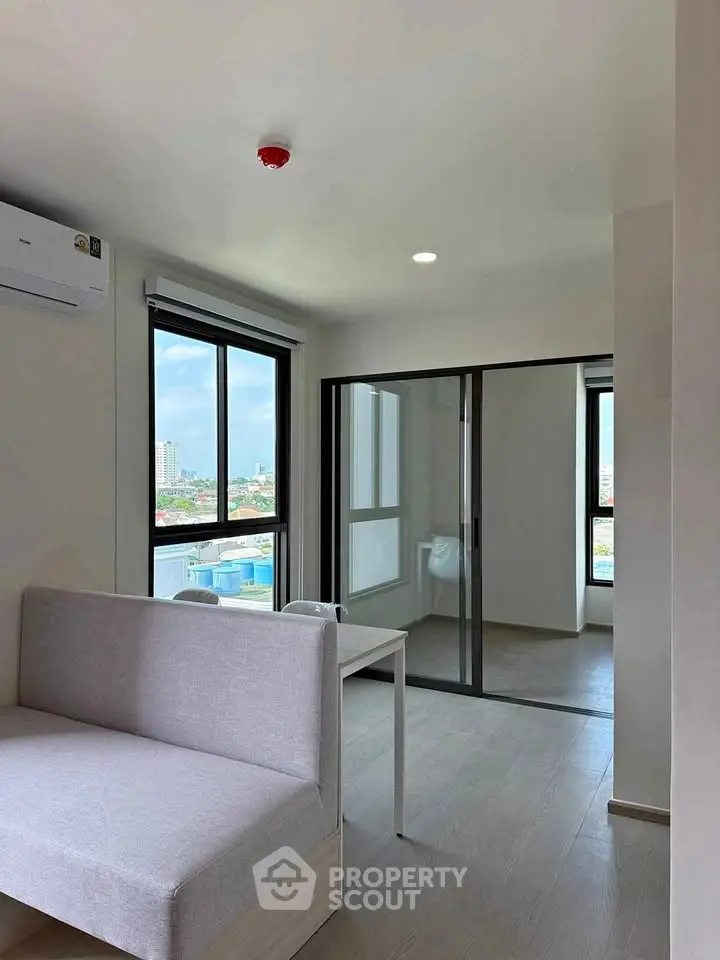 Modern apartment interior with large windows and sliding glass doors, offering a bright and airy living space.