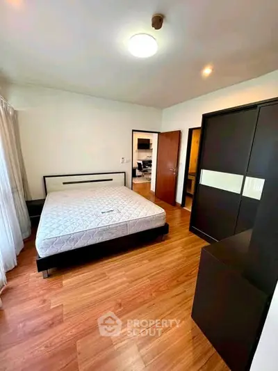 Spacious bedroom with modern furnishings and wooden flooring in a stylish apartment.