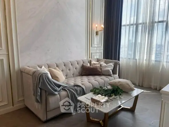 Luxurious living room with elegant sofa and marble coffee table, featuring large windows and stylish decor.