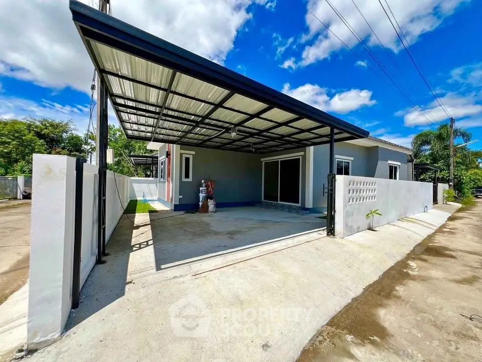 Modern single-story house with spacious carport and sleek exterior design under a clear blue sky.