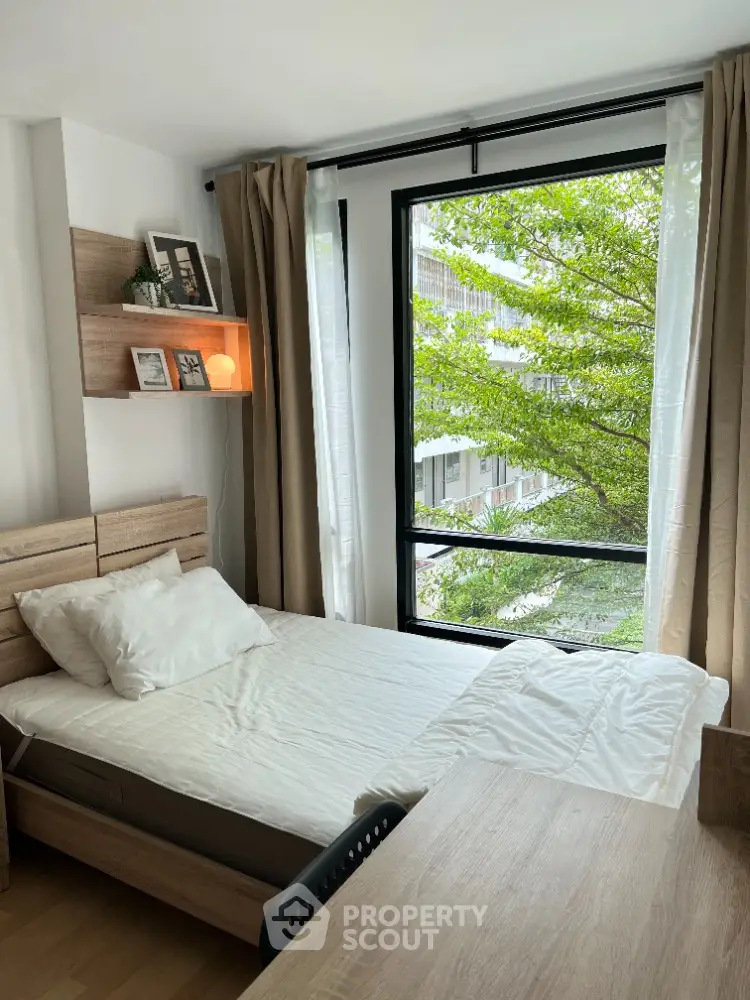 Cozy bedroom with large window and natural light in modern apartment