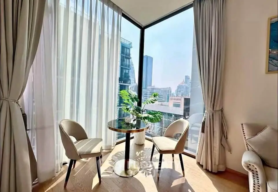 Bright corner unit with floor-to-ceiling windows and city view, featuring elegant seating area.