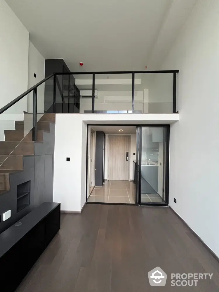 Modern duplex apartment with sleek staircase and glass balcony, featuring open layout and high ceilings.