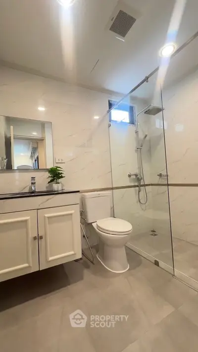 Modern bathroom with glass shower and sleek white fixtures.