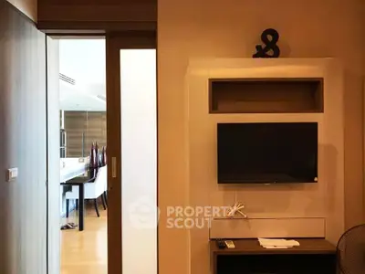 Modern interior with sleek TV setup and sliding door leading to dining area.