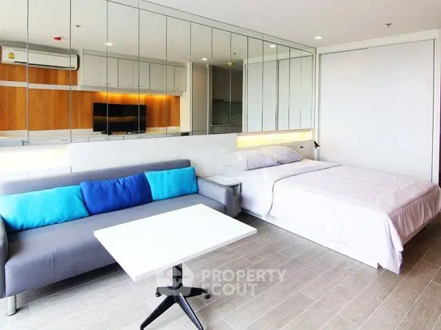 Modern studio apartment with mirrored wall and cozy furnishings